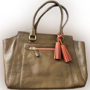 Brown coach bag with gold zipper and red tassel.
